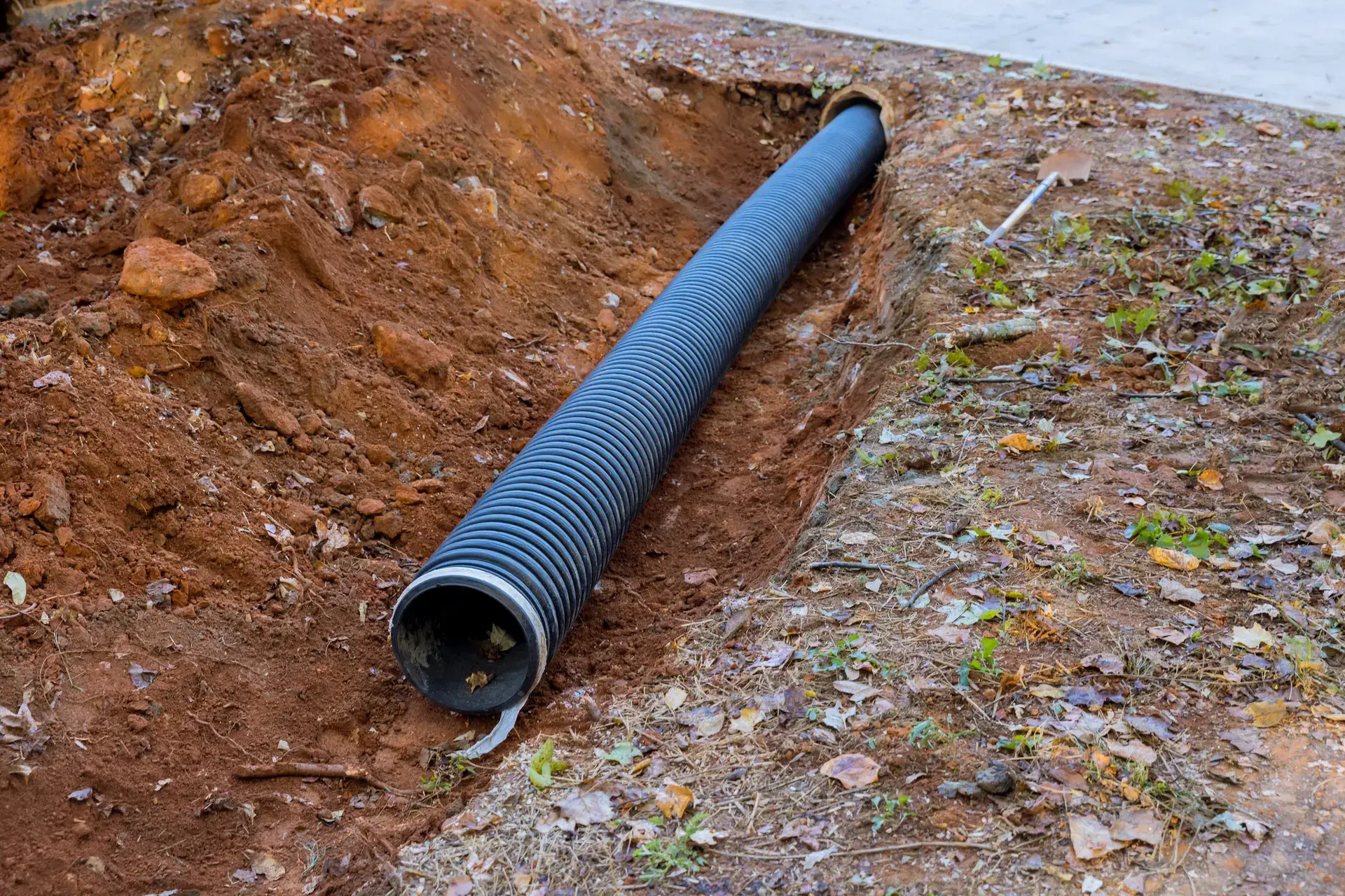 Black corrugated pipe set in a freshly dug trench