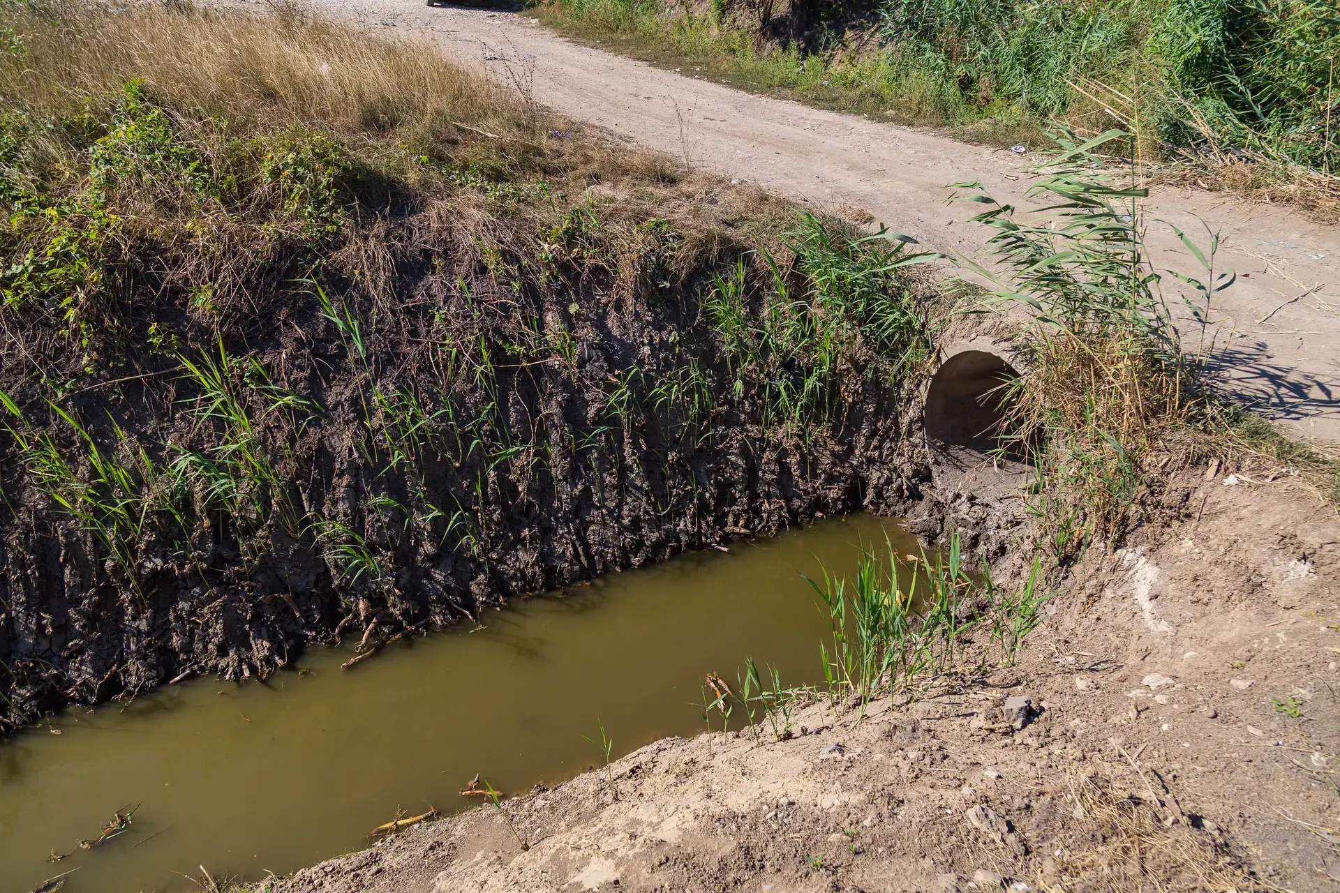 Culvert pipe carrying a roadside ditch under a gravel road