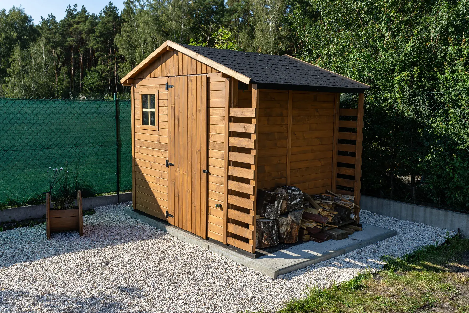 Wooden storage shed sitting on a level pad surrounded by crushed stone
