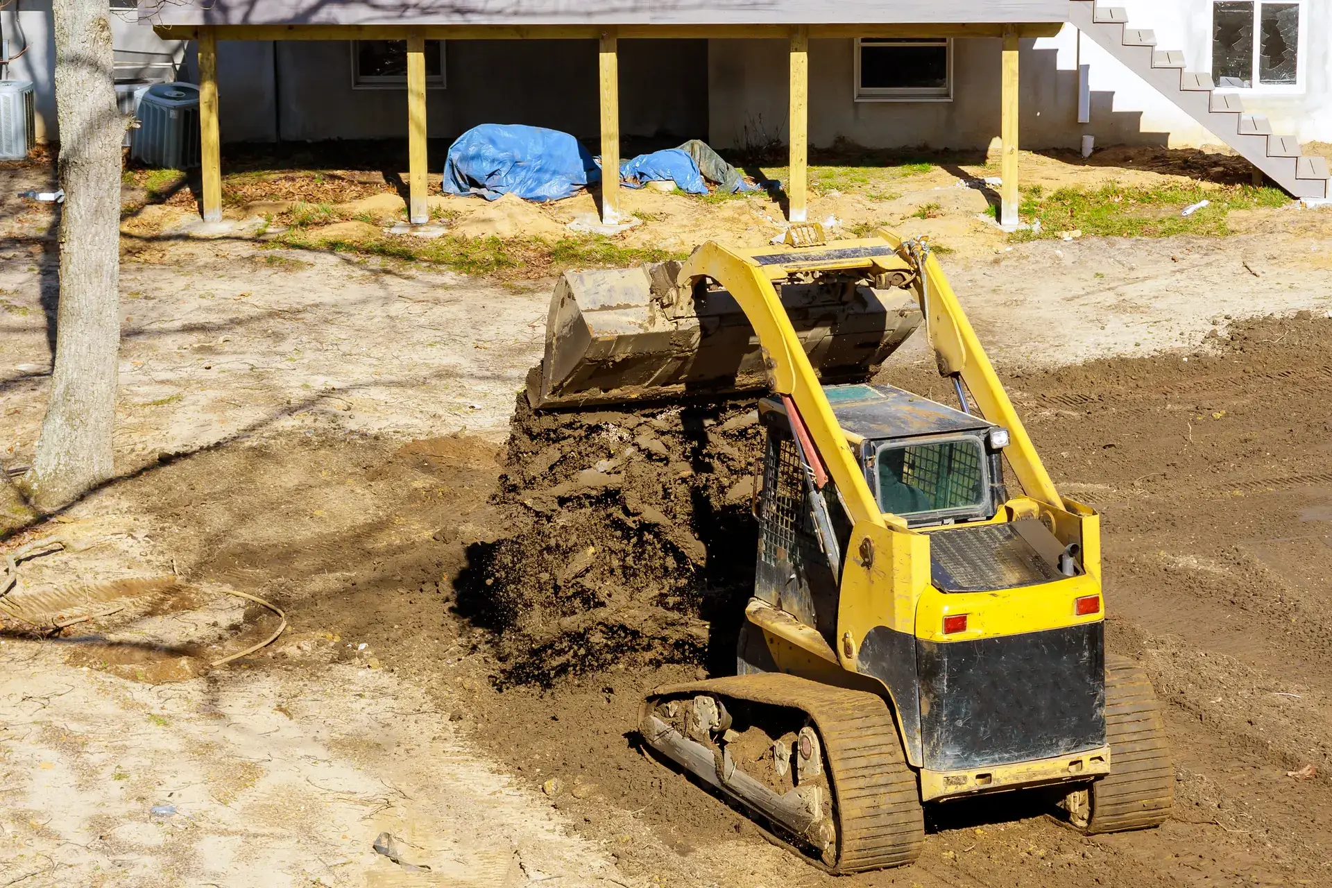 Track loader moving dirt beside a house under construction